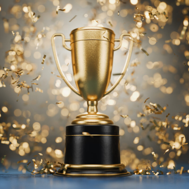 3D-rendered gold trophy cup with handles on a reflective surface, representing a first-place gaming achievement.