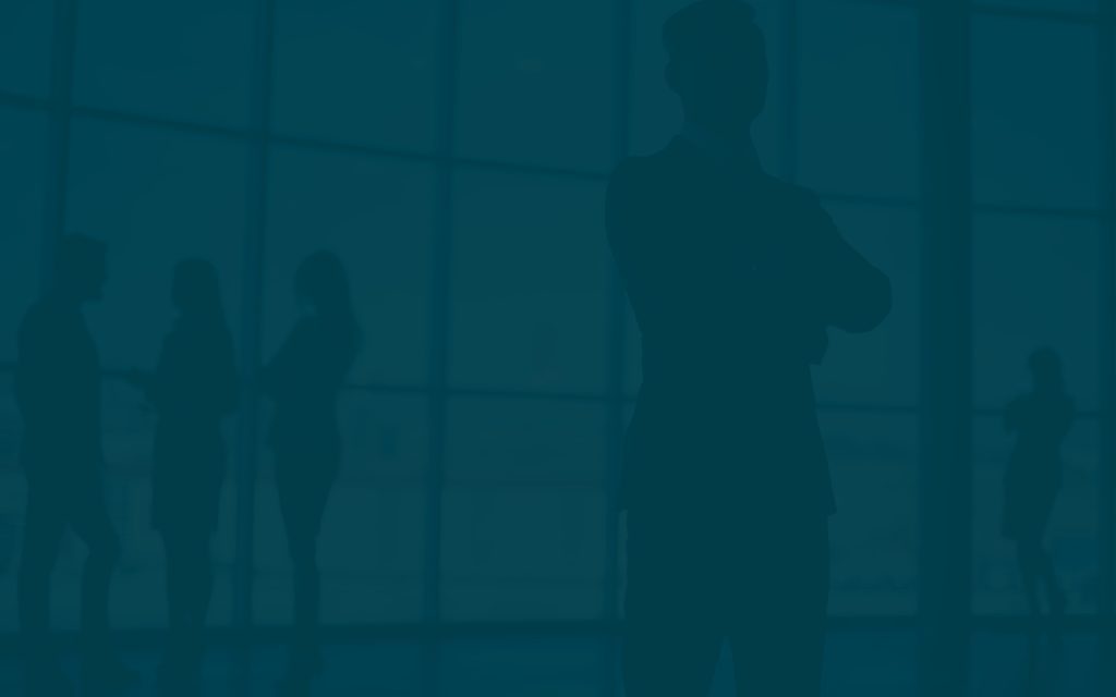 Group of silhouetted professionals engaged in conversation near large office windows during daylight