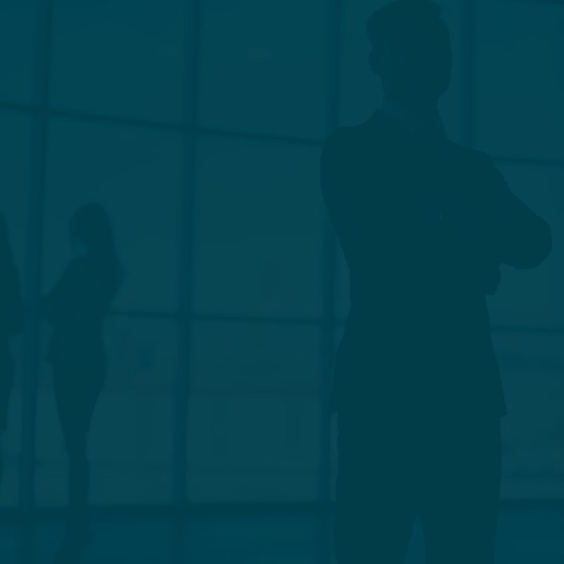 Group of silhouetted professionals engaged in conversation near large office windows during daylight