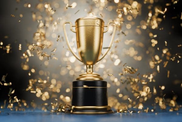 3D-rendered gold trophy cup with handles on a reflective surface, representing a first-place gaming achievement.